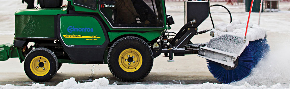 A snow clearing machine in Edmonton, with a brush made up of long blue plastic bristles.