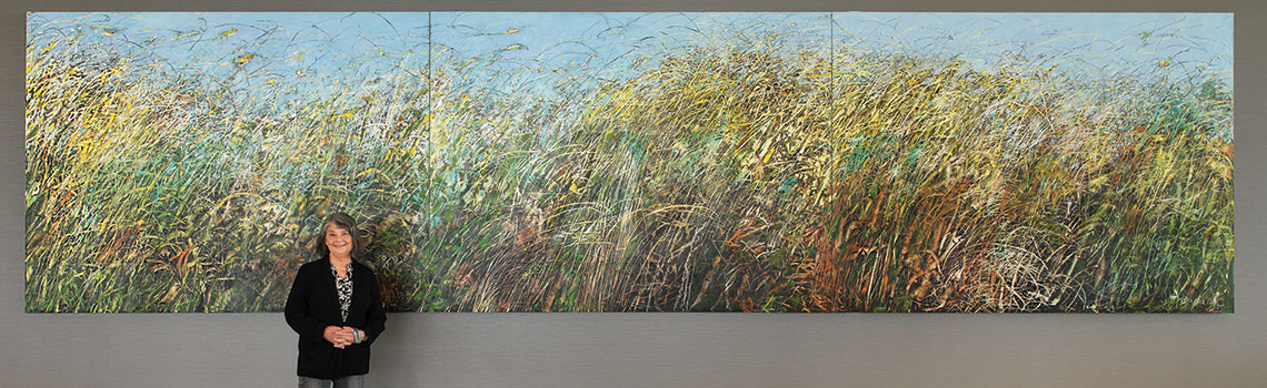 Teresa Posyniak standing in front of "Grasslands Tapestry"