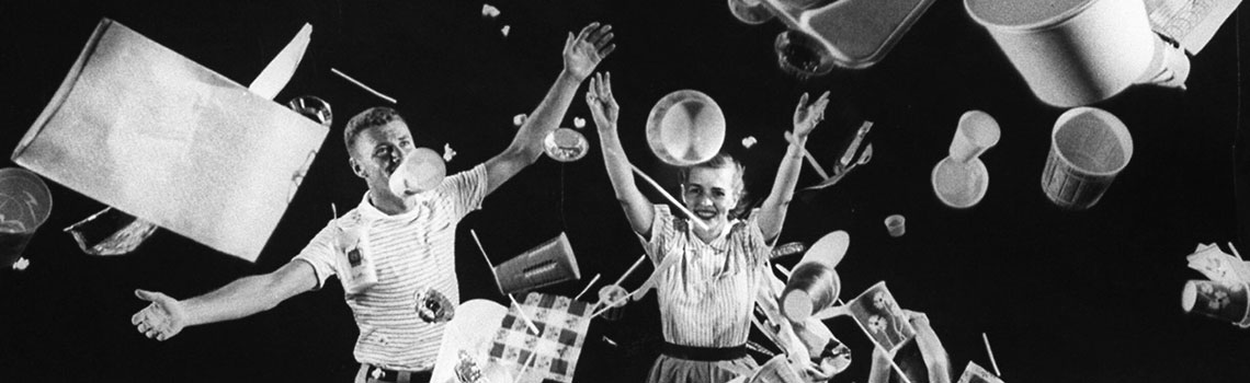 A family throwing plastic cups and plates into the air. A black and white photo from 1955 LIFE magazine article "Throwaway Living."