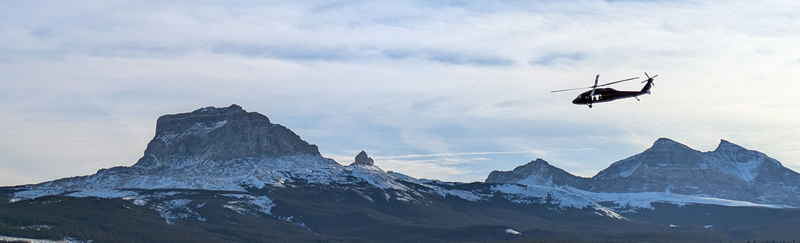 A Black Hawk Helicopter flying in front of the Rocky Mountains