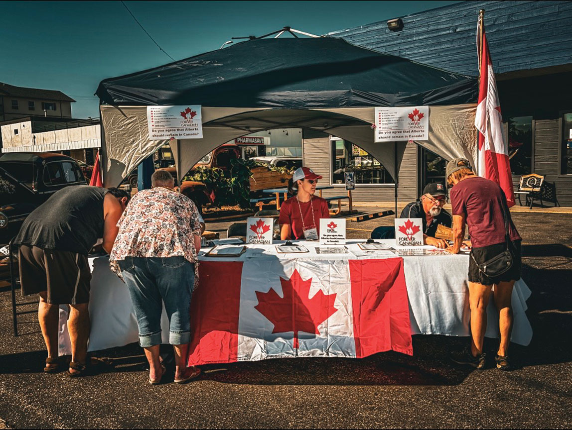 People Signing the Forever Canadian petition in Innisfail at a table with a large canada flag draped across it