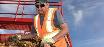 Elmer Crookedneck next to a pallet of potatoes. one of the Cree workers in alberta